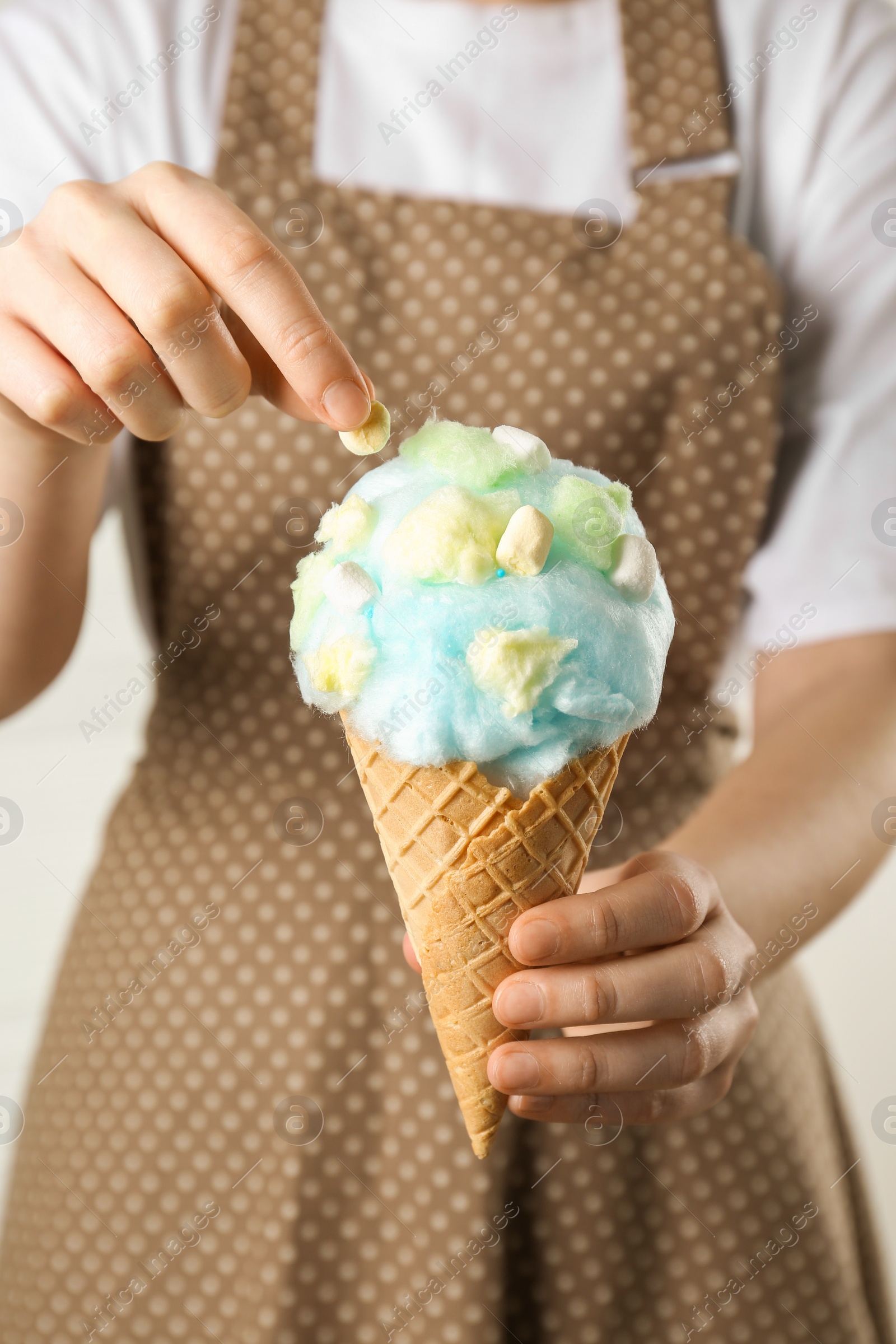 Photo of Woman holding waffle cone with cotton candy, closeup