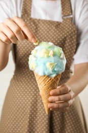 Photo of Woman holding waffle cone with cotton candy, closeup