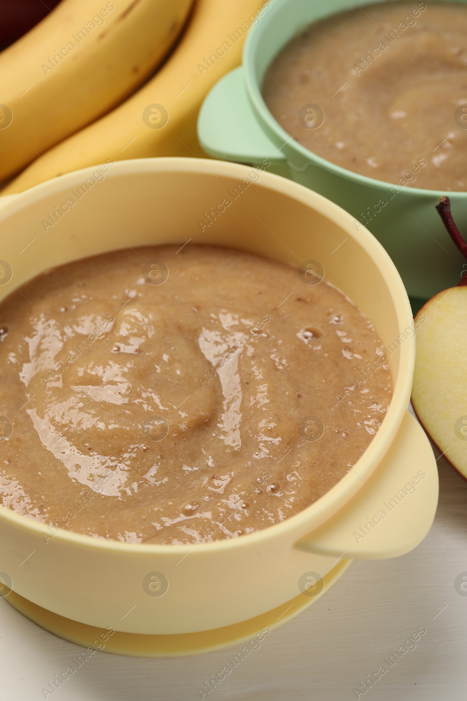 Photo of Bowls with banana puree on white table. Baby food