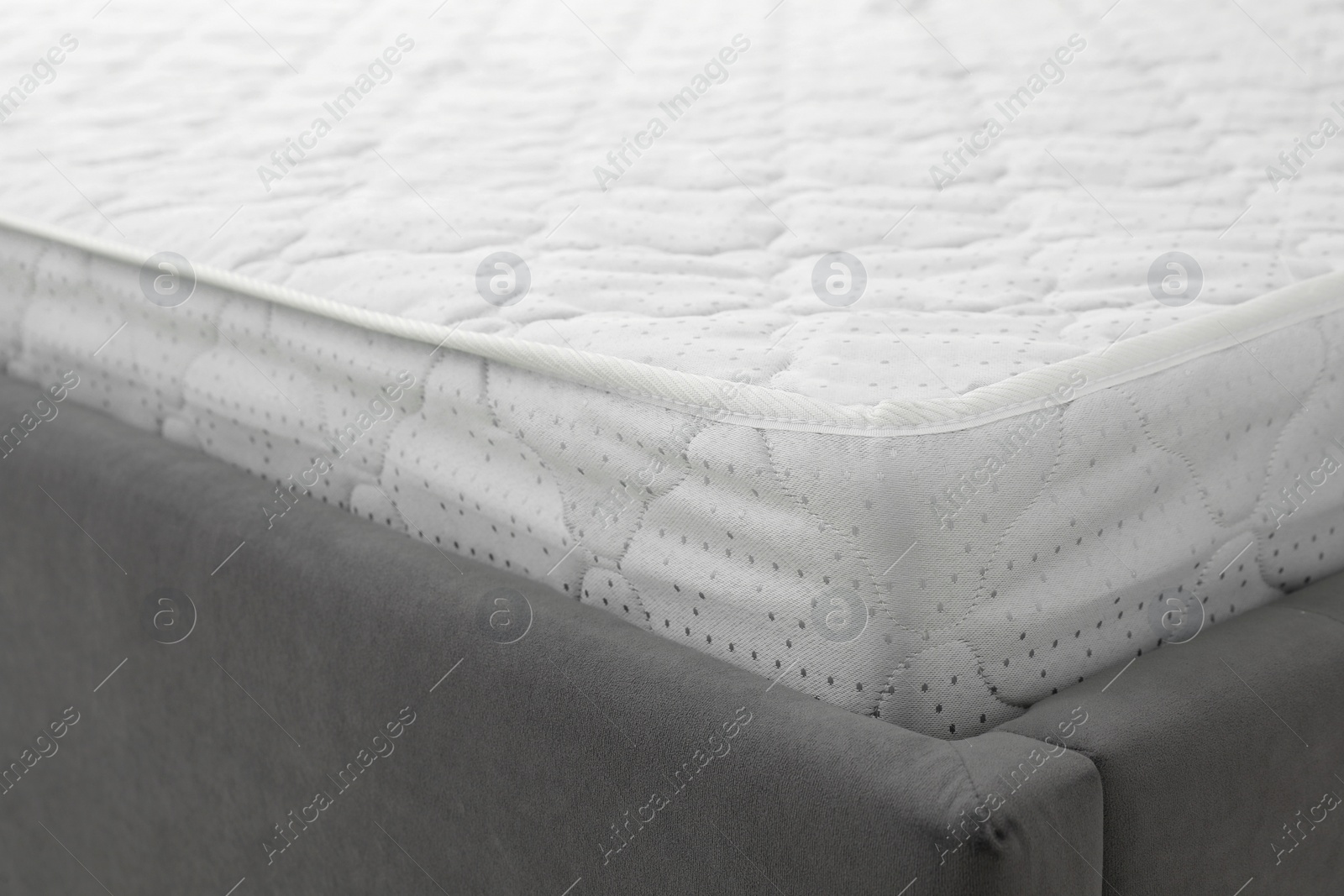 Photo of New light green mattress on gray bed, closeup