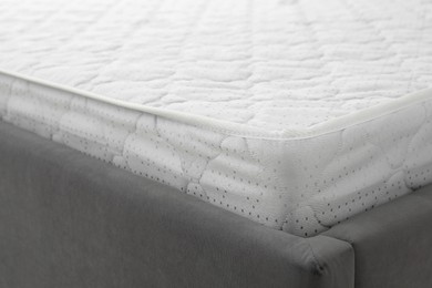 Photo of New light green mattress on gray bed, closeup