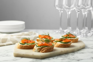 Photo of Tasty canapes with salmon, cucumber and cream cheese on white marble table