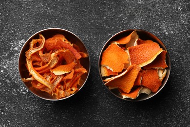 Photo of Bowls with dry orange peels on gray textured table, flat lay