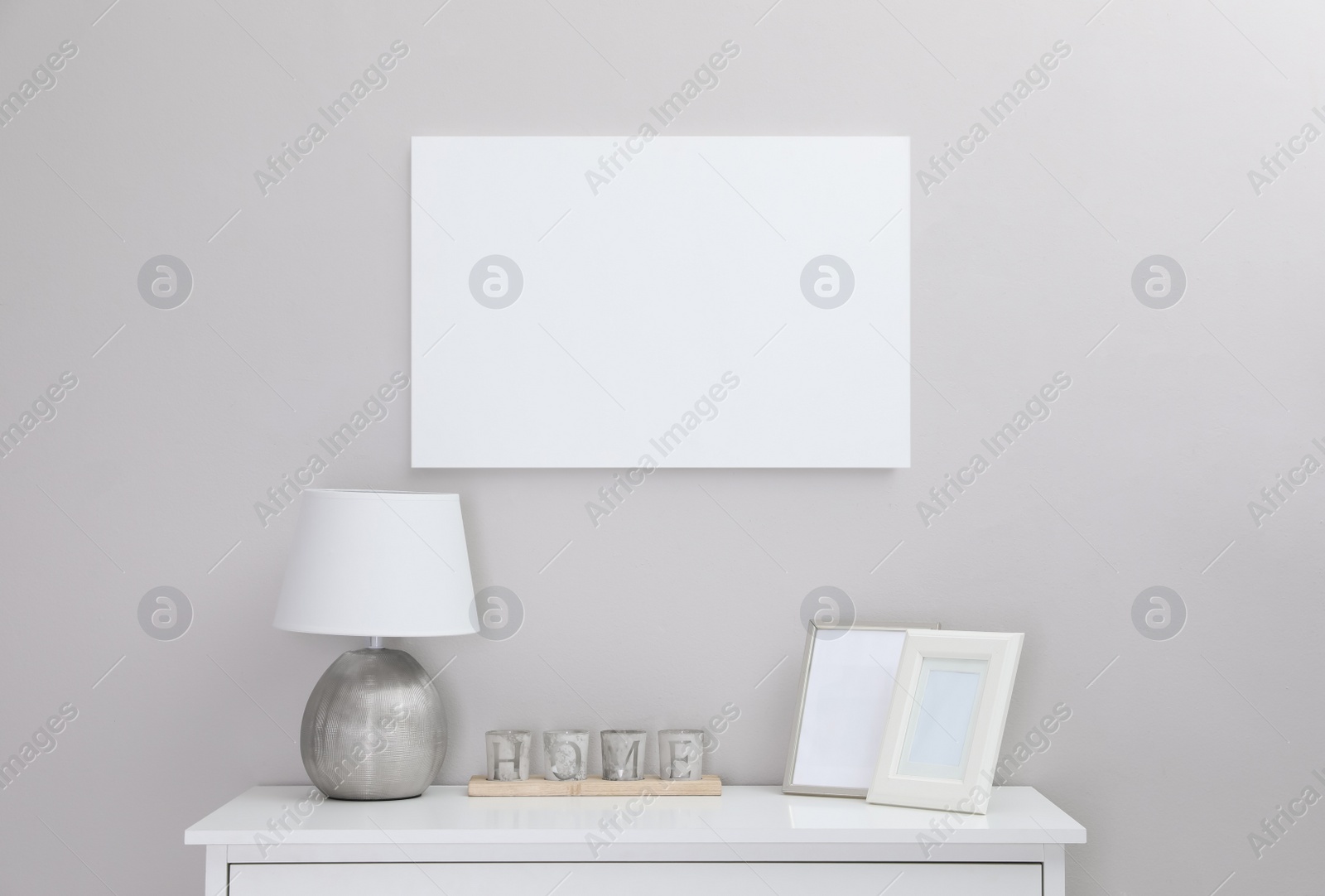 Photo of Blank canvas on wall over console table with decor indoors. Space for design