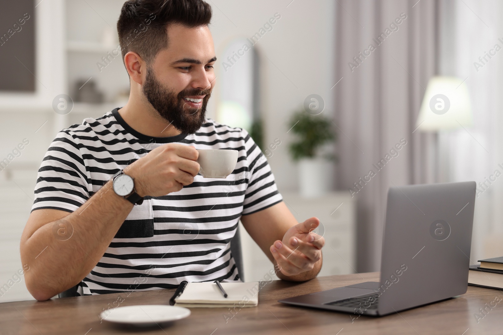 Photo of Young man using video chat during webinar at table in room