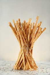 Photo of Delicious grissini sticks on white marble table