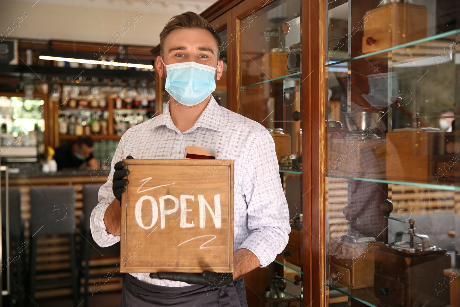 Photo of Waiter holding OPEN sign in restaurant. Catering during coronavirus quarantine