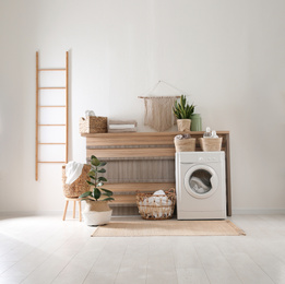 Photo of Modern washing machine and plants in laundry room interior