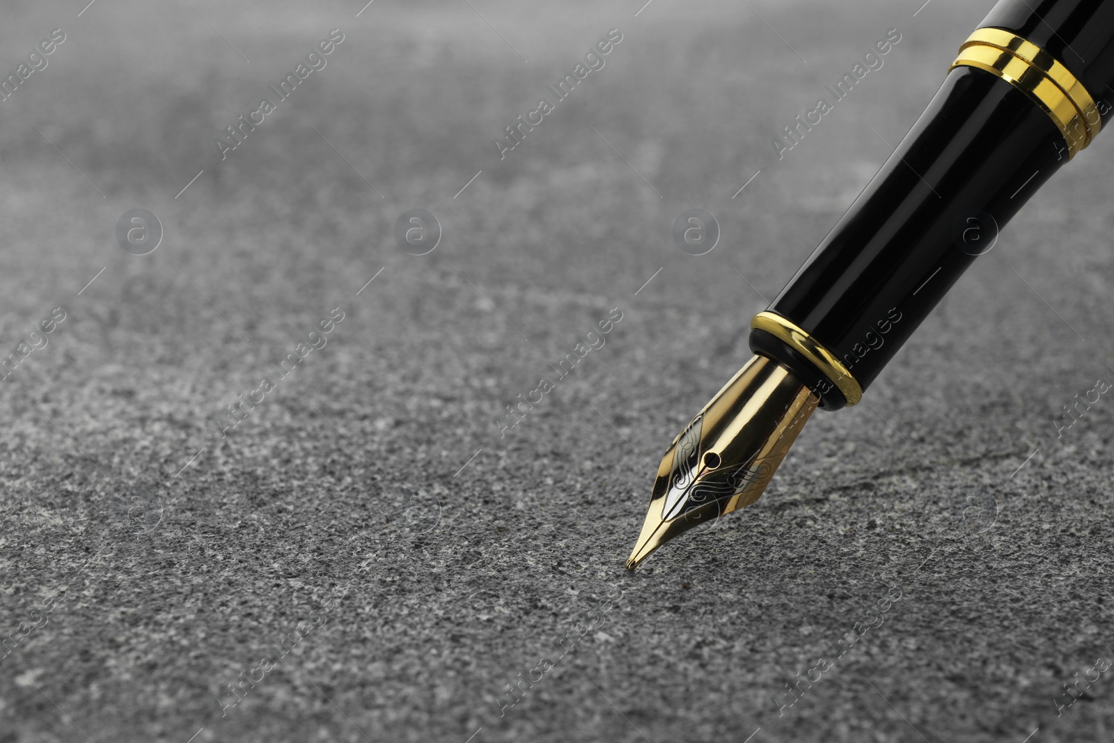 Photo of Stylish fountain pen on grey textured table, closeup. Space for text