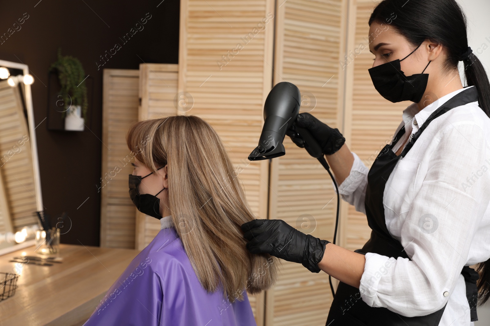 Photo of Professional stylist working with client in beauty salon. Hairdressing services during Coronavirus quarantine