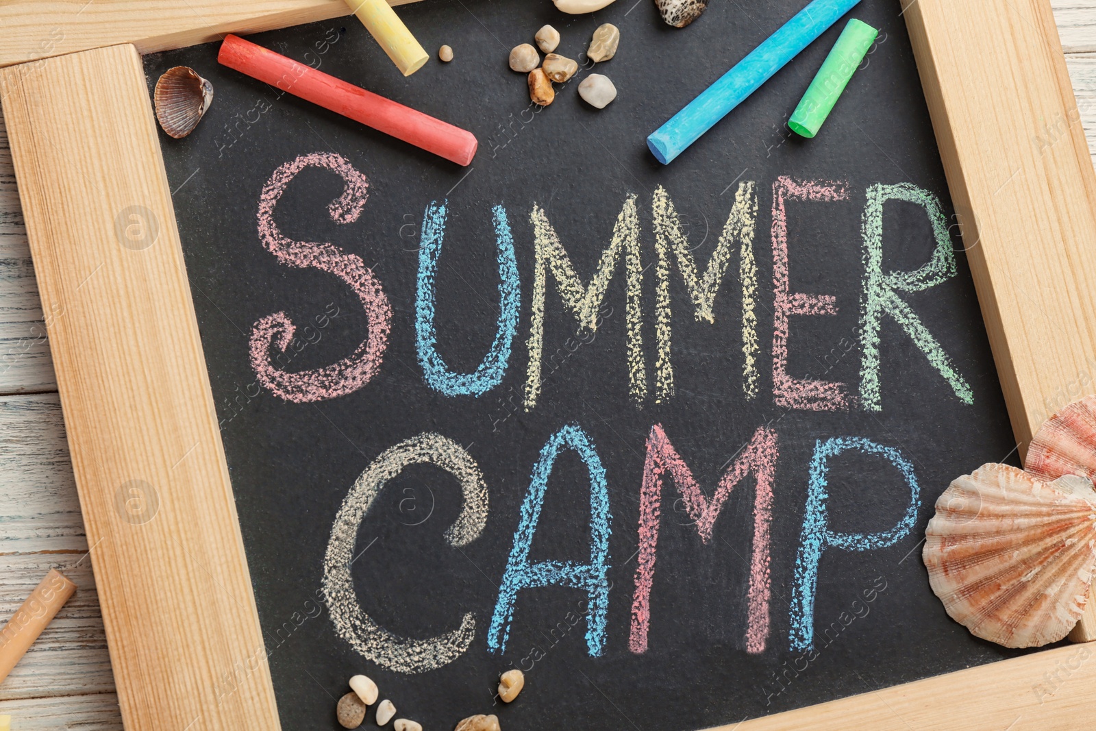 Photo of Text "SUMMER CAMP" on small blackboard and colorful chalk, top view