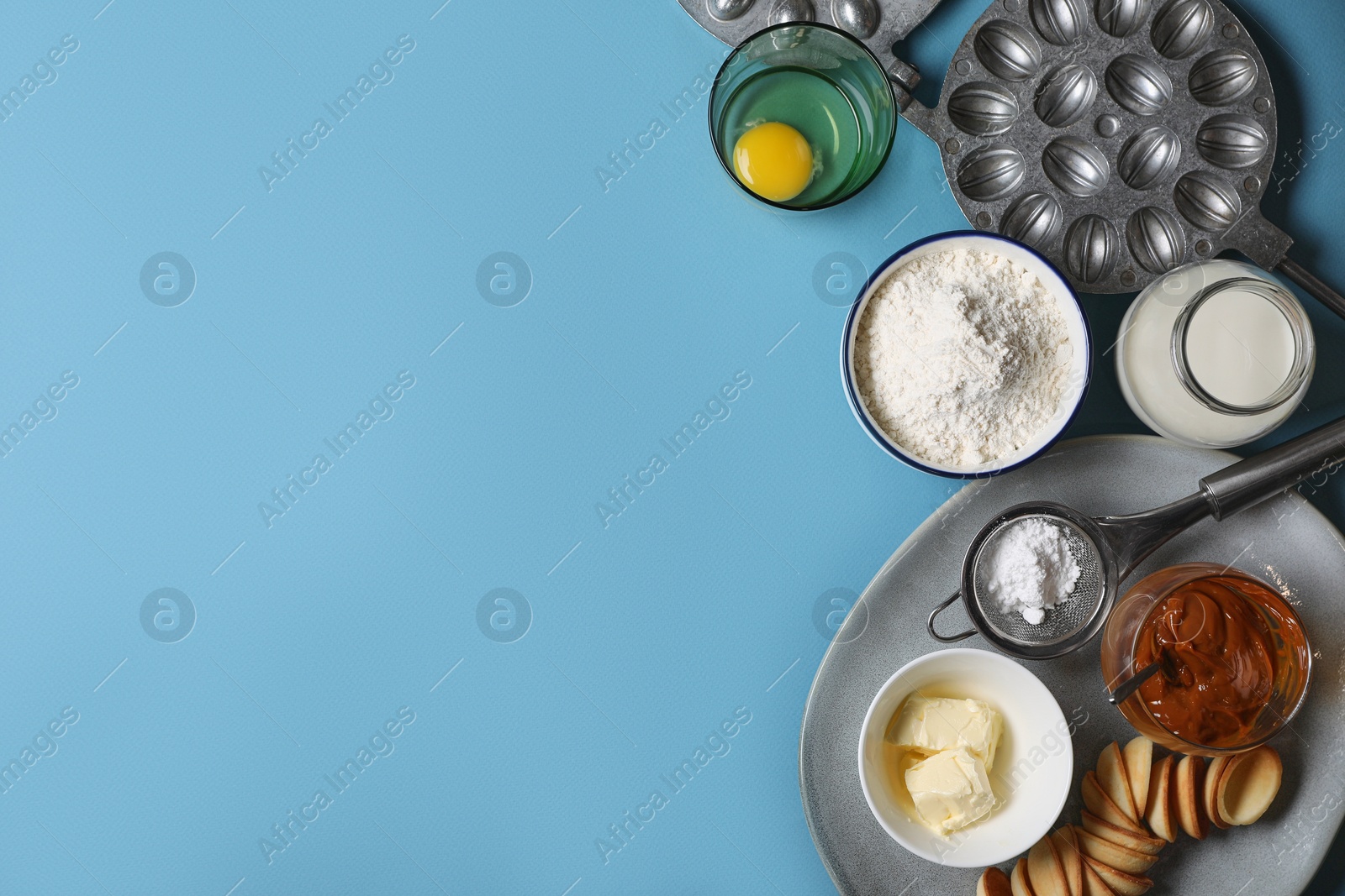 Photo of Baking mold and ingredients for walnut shaped cookies on light blue table, flat lay. Space for text