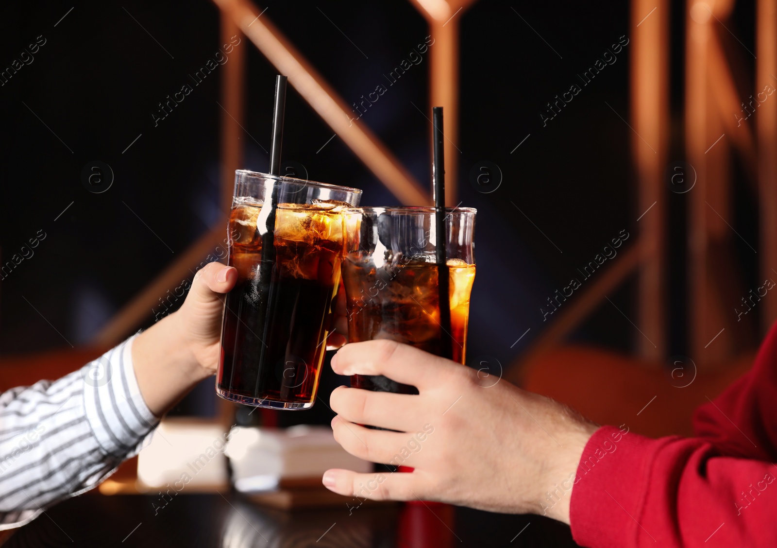 Photo of Young couple with glasses of refreshing cola at table indoors, closeup