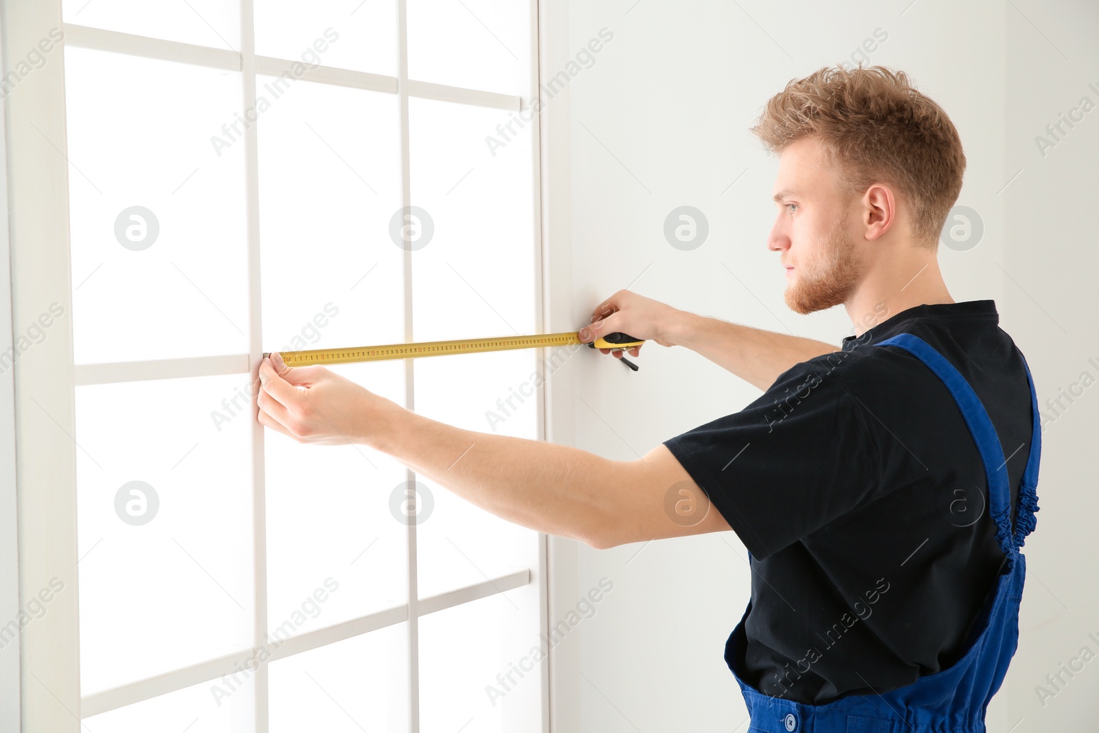 Photo of Service man measuring window for installation indoors