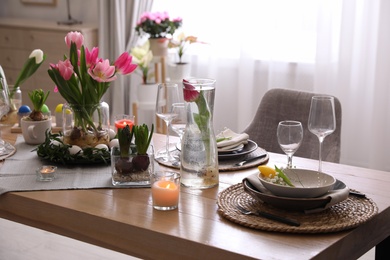 Photo of Beautiful Easter table setting with beautiful flowers indoors