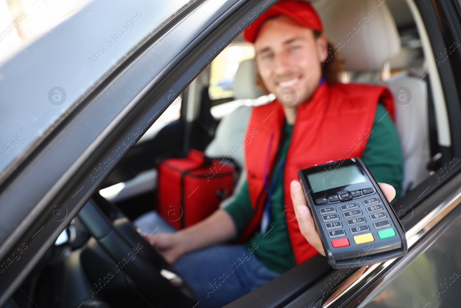 Photo of Male courier with terminal in car. Food delivery service