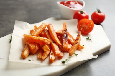 Board with sweet potato fries on grey table, closeup