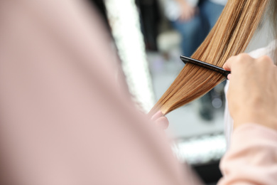 Photo of Professional hairdresser working with client in beauty salon, closeup