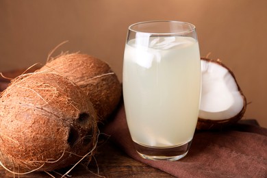 Glass of coconut water and nuts on wooden table