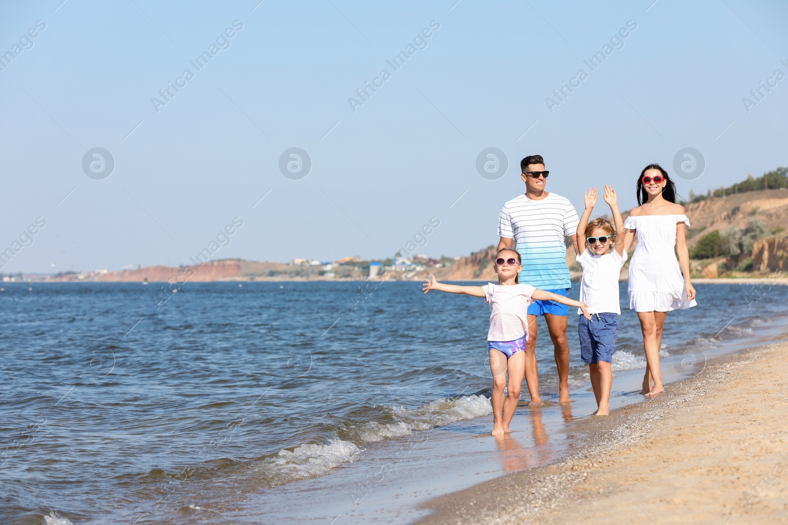 Photo of Happy family walking on sandy beach near sea. Summer holidays