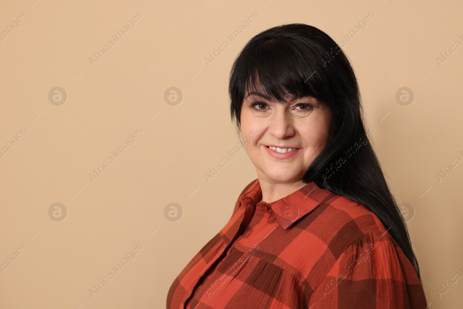 Photo of Beautiful overweight mature woman with charming smile on beige background. Space for text