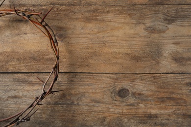 Photo of Crown of thorns on wooden background, top view with space for text. Easter attribute