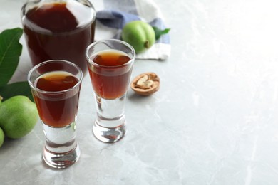 Photo of Delicious liqueur and fresh walnuts on light grey table. Space for text