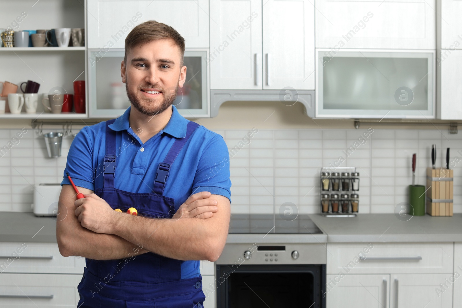 Photo of Portrait of repairman with tools near oven in kitchen. Space for text