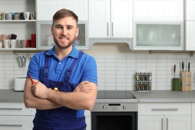 Photo of Portrait of repairman with tools near oven in kitchen. Space for text