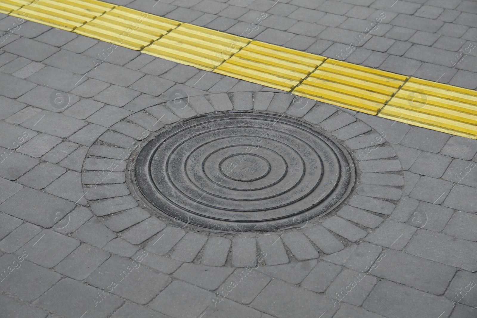 Photo of Metal sewer hatch on street tiles outdoors