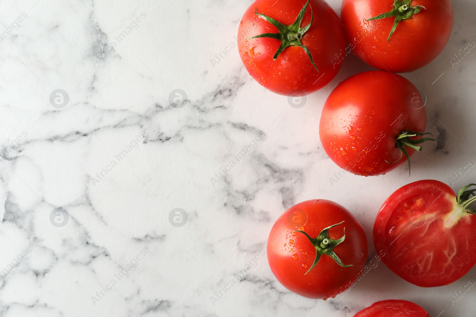Photo of Fresh ripe tomatoes on white marble table, flat lay. Space for text