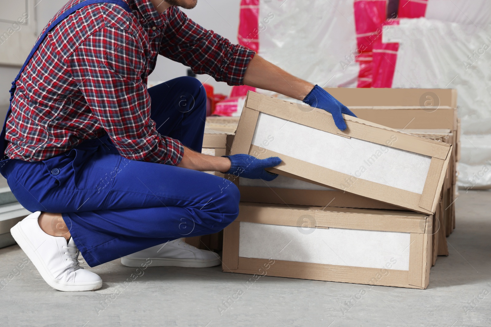 Photo of Construction worker with packed new boxes in room prepared for renovation, closeup