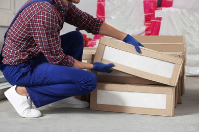 Construction worker with packed new boxes in room prepared for renovation, closeup