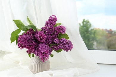 Beautiful lilac flowers in vase on windowsill