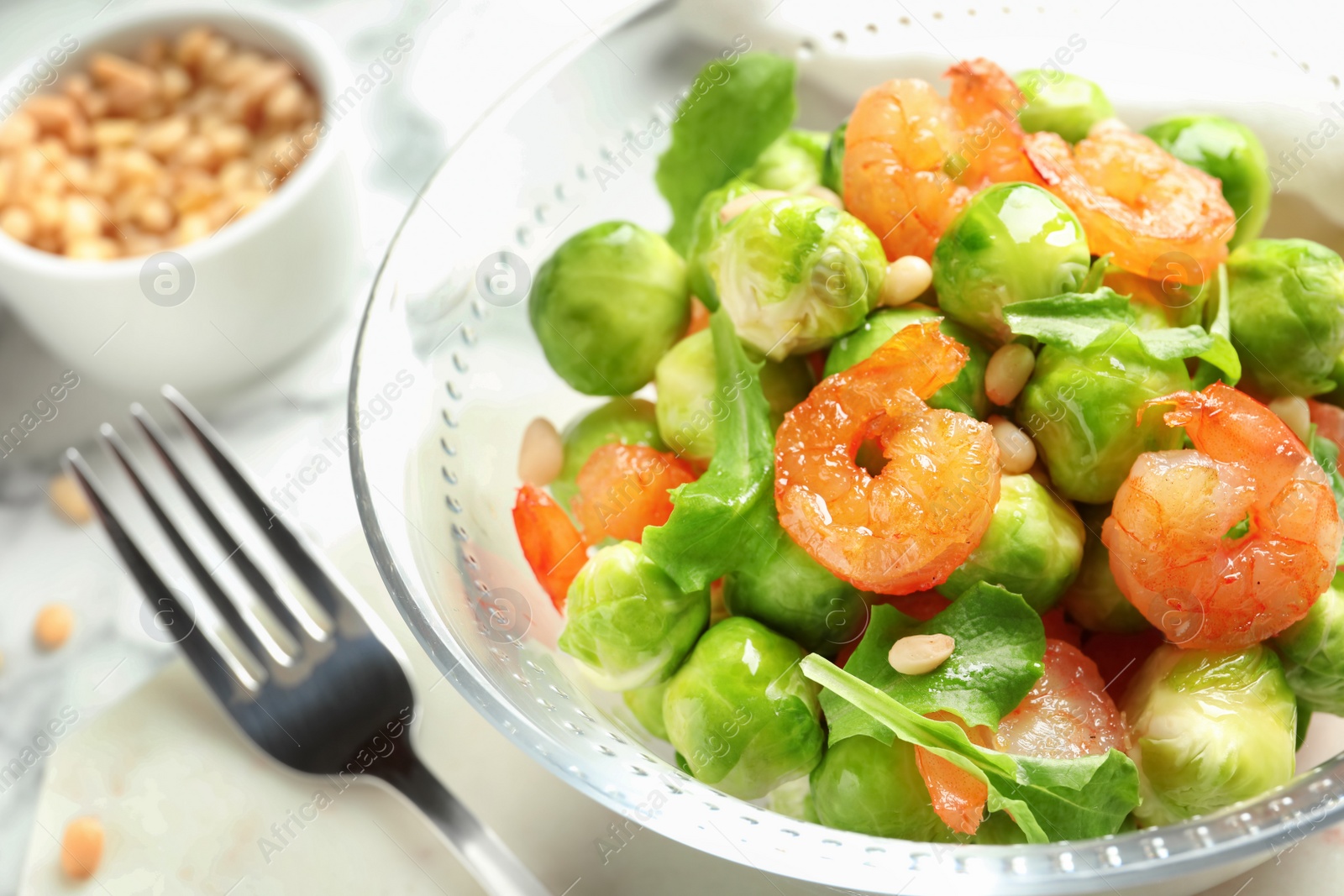 Photo of Bowl of delicious salad with Brussels sprouts and shrimps on table