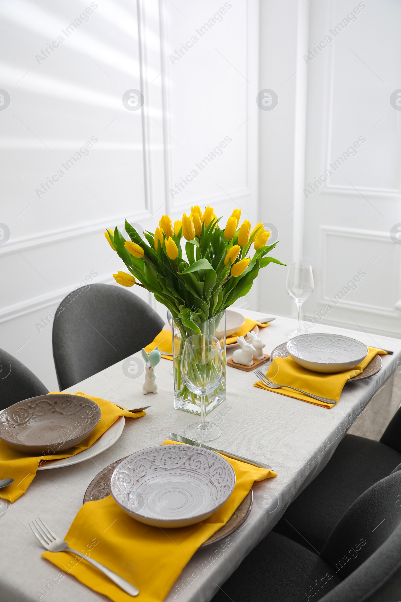 Photo of Beautiful Easter table setting with yellow tulips indoors