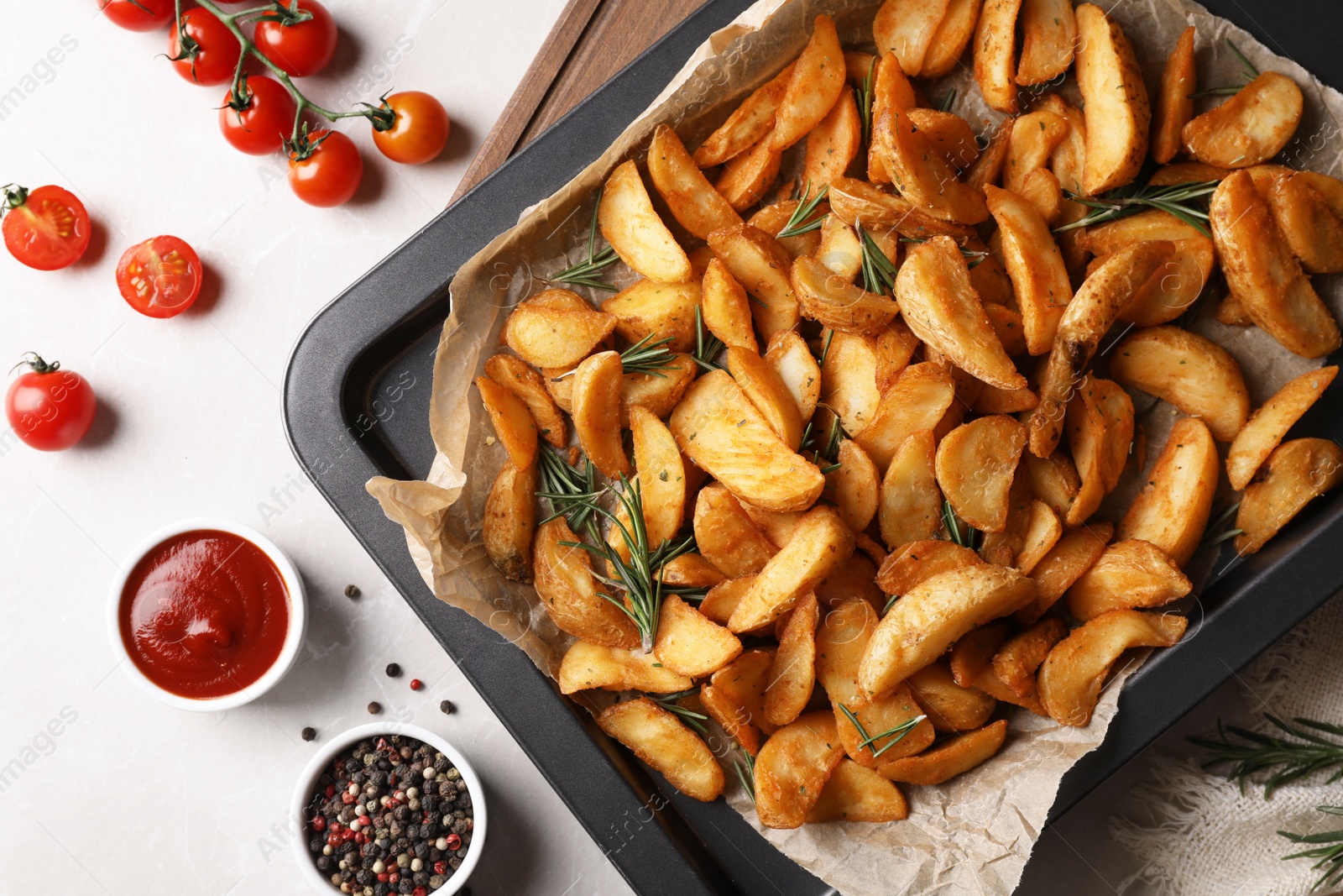 Photo of Flat lay composition with baked potatoes and rosemary in baking sheet on table