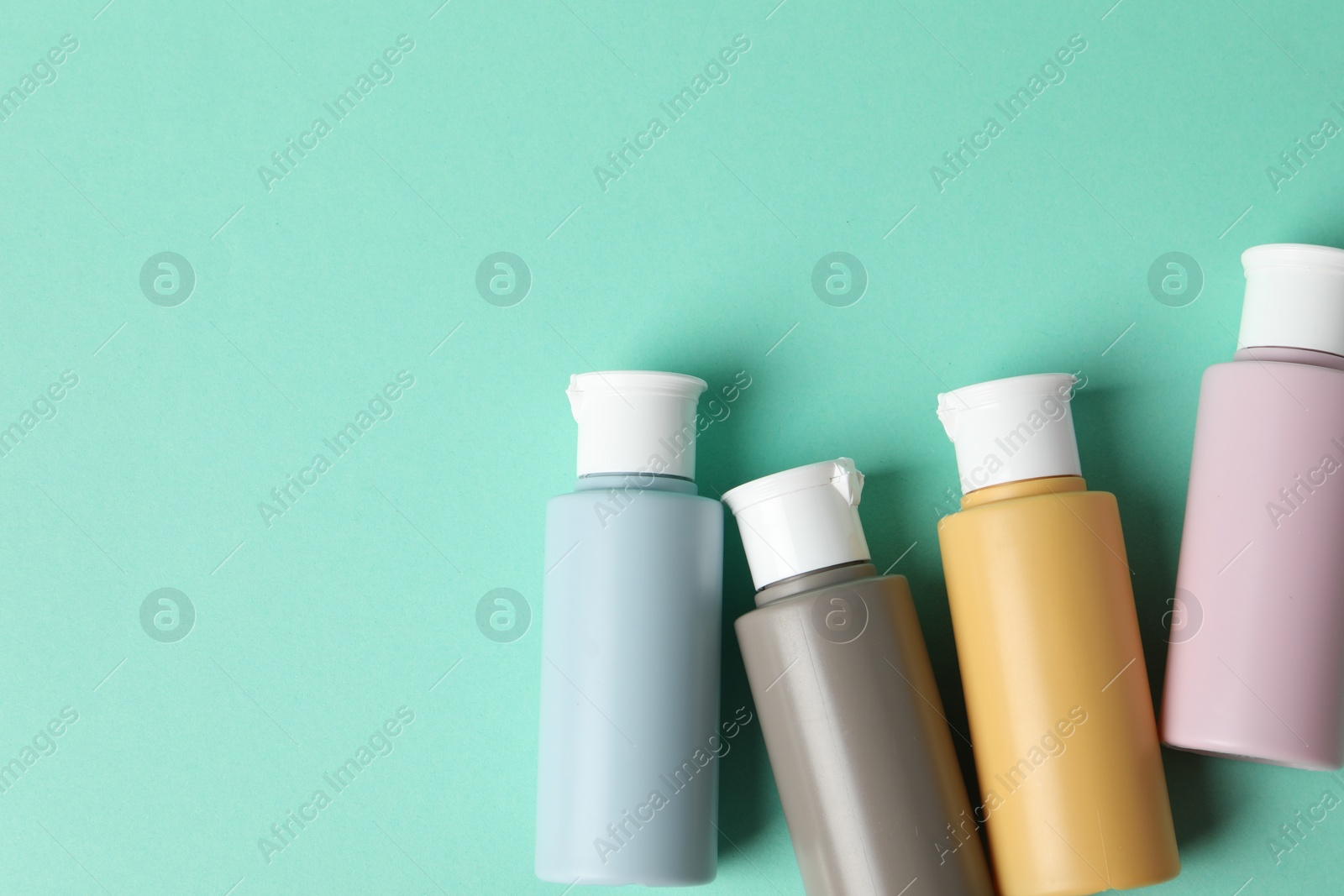 Photo of Cosmetic travel kit on turquoise background, flat lay. Space for text