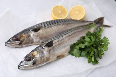 Tasty salted mackerels, parsley and cut lemons on white table, closeup