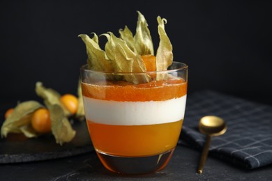 Delicious dessert decorated with physalis on black table