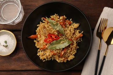 Photo of Delicious pilaf and bay leaves served on wooden table, flat lay