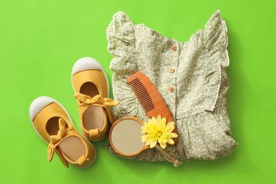 Stylish child clothes, shoes and accessories on green background, flat lay