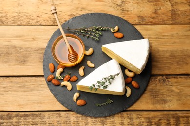 Photo of Tasty Camembert cheese with thyme, honey and nuts on wooden table, top view