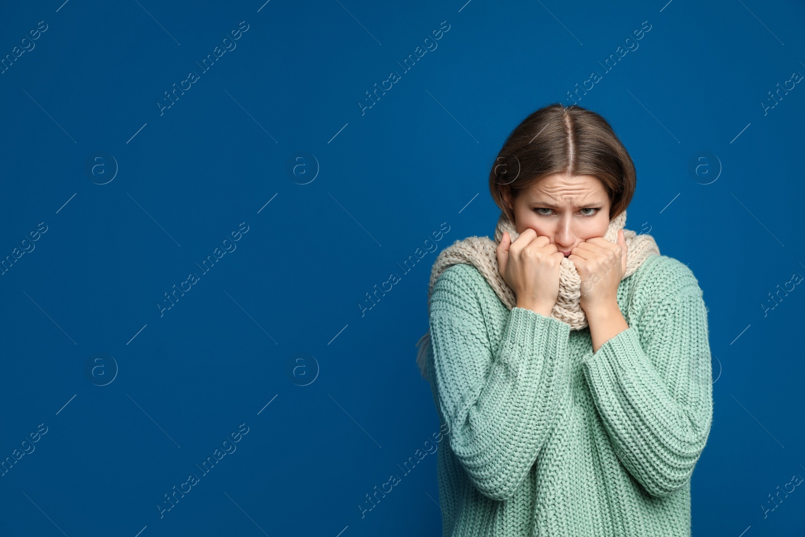 Image of Young woman wearing scarf suffering from fever on blue background, space for text. Cold symptoms