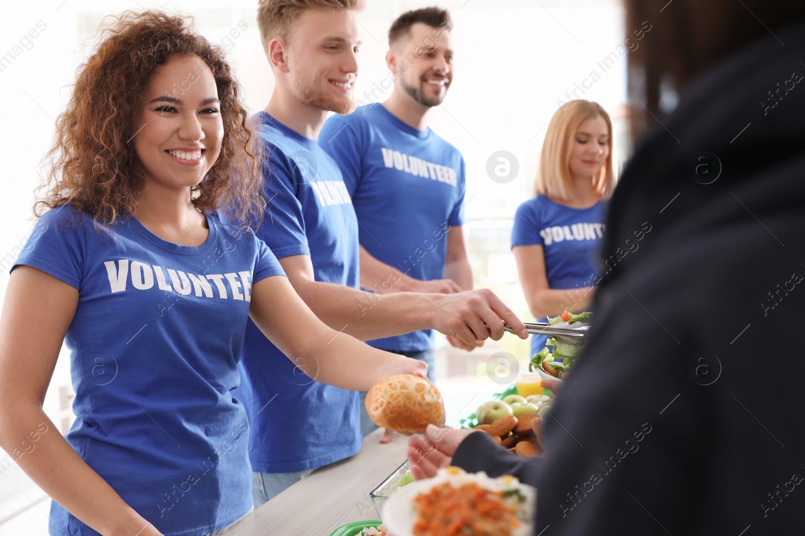 Photo of Volunteers serving food to poor people indoors