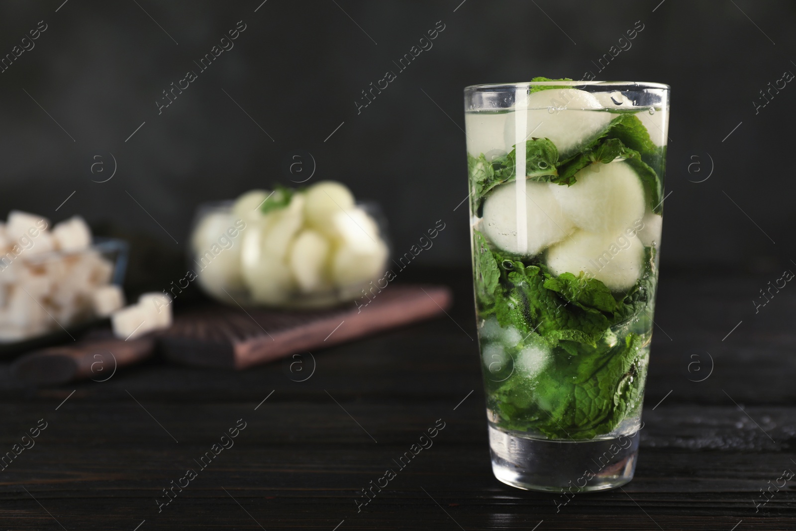 Photo of Glass with tasty melon ball drink on dark table