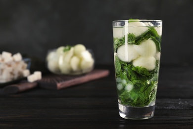 Glass with tasty melon ball drink on dark table