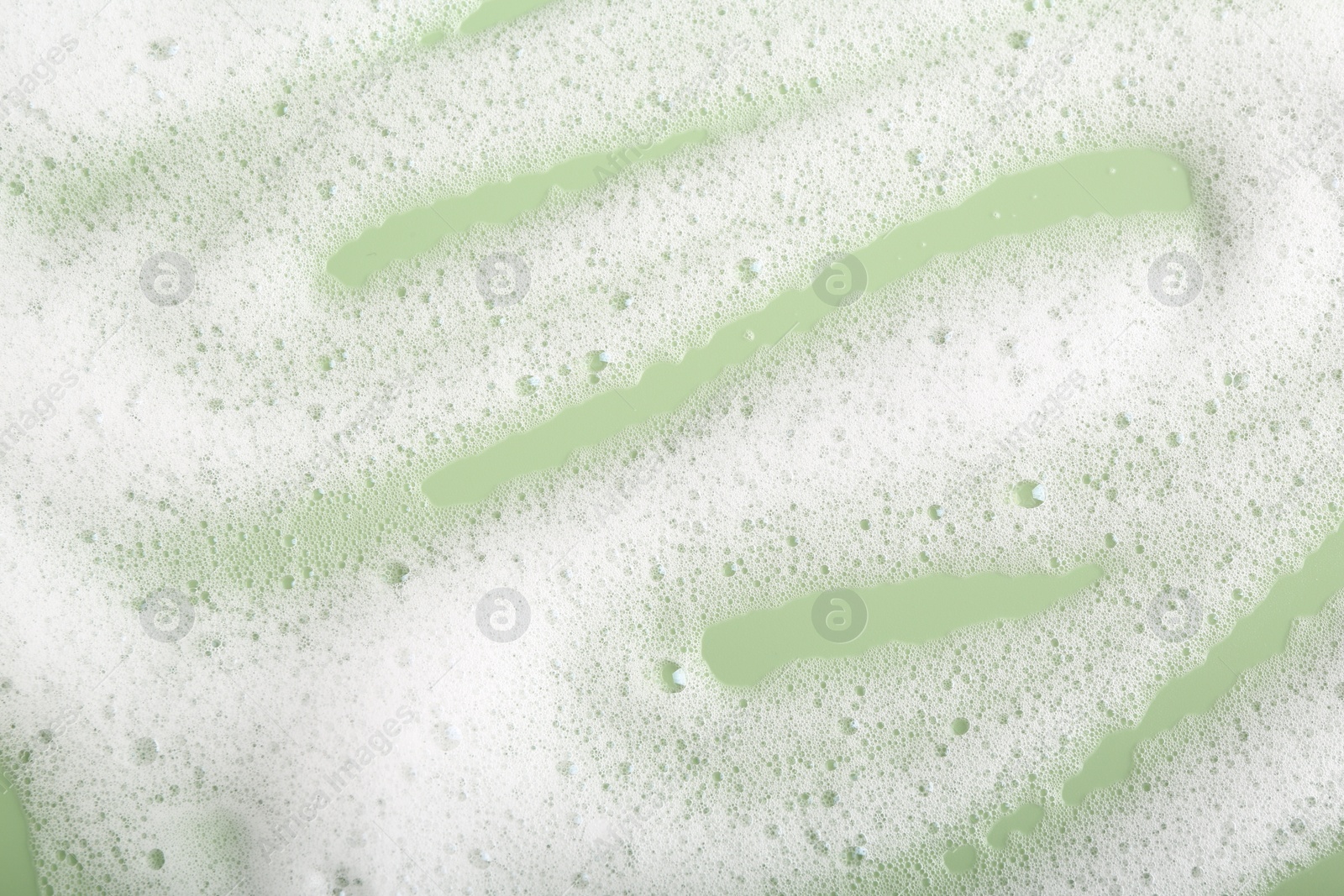 Photo of White fluffy foam on green background, top view