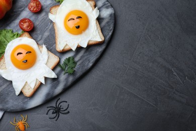 Photo of Halloween themed breakfast served on black table, flat lay and space for text. Tasty toasts with fried eggs in shape of ghost