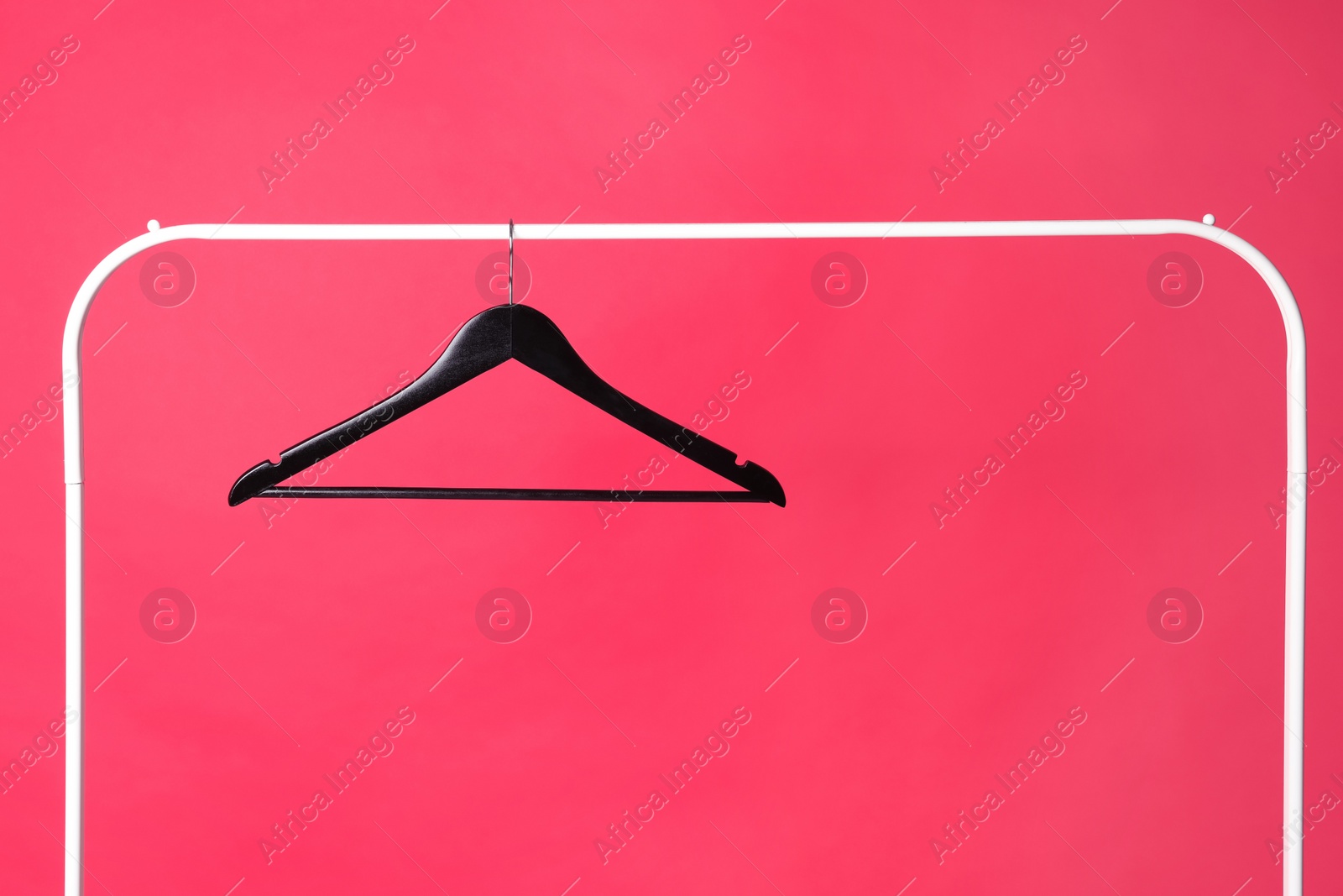Photo of Black clothes hanger on metal rack against color background